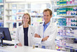 © ArcursForPI/peopleimages.com - Pharmacy, man and woman in portrait with smile, confidence and prescription drugs in clinic. Teamwork, advice and pharmacist with arms crossed, medicine and pills for medical service at counter