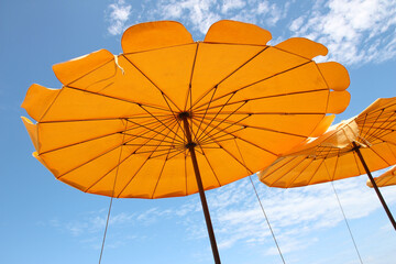 Yellow beach umbrella on blue sky and white clouds