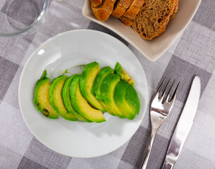 Wall Mural - Beautifully sliced ​​avocado with sesame seeds on a plate, serving avocado on a holiday table