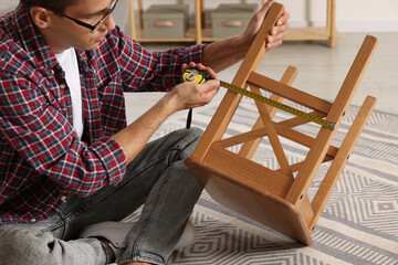 Sticker - Man using tape measure while repairing wooden stool indoors