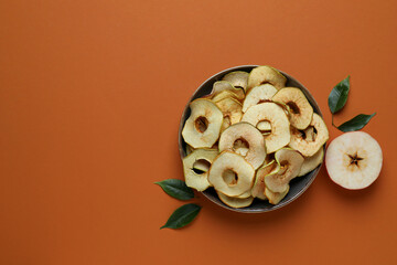 Apples dried slices and half of apple on brown background, space for text