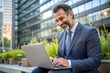 © Introvertia - Smiling businessman working on laptop in urban garden setting