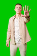 © fotofabrika - Man Holding Up Hand Against Bright Green Background While Displaying Serious Expression