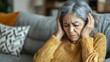 © Siasart - A distressed elderly woman holding her head in discomfort.