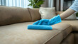 © Siasart - A person cleaning a couch with a blue cloth and gloves.