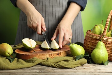 Wall Mural - Woman cutting fresh green pears at wooden table, closeup