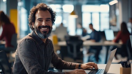 Poster - smiling professional man working on laptop in modern office environment with colleagues in backgroun