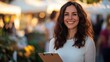 © nakarin - Smiling Woman Holding Clipboard at Outdoor Market with Warm Lighting and Bokeh Background