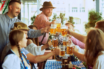 Cheers. Happy, smiling, joyful people,friends gathering at bar, clinking glasses in celebratory toast, enjoying positive meeting. Concept of Oktoberfest, festival, party, brewery and traditions