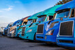 © vit - Big rigs semi trucks with semi trailers standing in row on truck stop parking lot take a break for truck driver rest