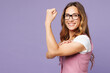 © ViDi Studio - Young strong successful employee business woman corporate lawyer wear white t-shirt vest glasses biceps muscles on hand demonstrating strength power look camera isolated on plain purple background.
