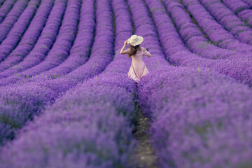 Wall Mural - A woman is walking through a field of purple flowers