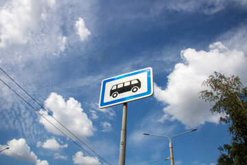 A bus stop sign set against a vivid blue sky filled with clouds