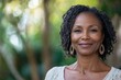 © ChaoticMind - Portrait of a woman with earrings smiling warmly in an outdoor setting surrounded by greenery, embodying a sense of peace, joy, and connection with nature through an organic, natural style.