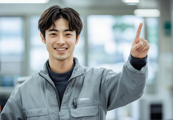 Canvas Print - A Japanese man in his thirties, wearing work , smiles and points to the upper left with one hand, set against an office background.