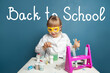 © millaf - Cute intelligent kid with welcome back to school lettering on blue chalkboard background