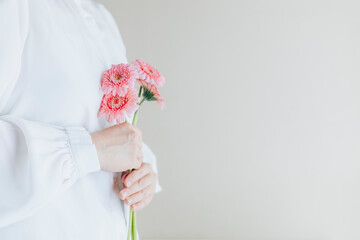 白背景、横向き、ガーベラの花束を持つ女性