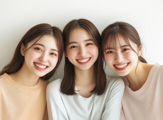 Wall Mural - Three Japanese women in their early to mid-20s, smiling and posing for the camera against a white background.