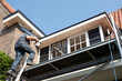 © Henk Vrieselaar - Construction worker walks up a ladder with a new window with rod division. Renovation house with double glazing