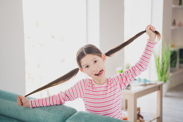 Wall Mural - Photo portrait of tongue out chiild little brunette girl staying at home playing touching her ponytails having fun isolated in her room