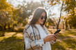 © mary_markevich - attractive young woman walking in autumn wearing jacket using phone