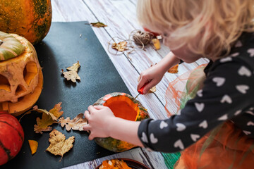 Carving a Pumpkin for Halloween. Getting ready for Halloween girl takes the top off a pumpkin that was carved to make a scary face on a jack-o'-lantern. Step to step. Step 2