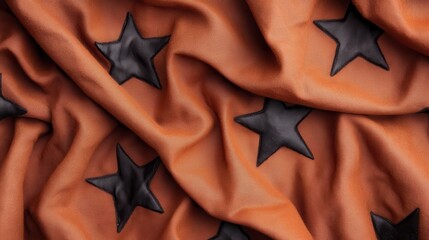 An artistic representation of black stars sewn onto orange cloth, showcasing the interplay of textures and colors in fabric design, emphasizing creativity and modern aesthetics.