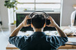 © Maskot - Rear view of male programmer wearing headphones in office