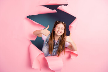 Poster - Photo portrait of adorable small girl thumb up approve ripped paper poster dressed stylish denim garment isolated on blue color background