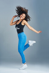 Poster - Happy woman, portrait and fun with energy in fashion for excitement, style or casual clothing on a gray studio background. Young, female person or excited model with smile, joy or outfit for freedom