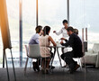 © ThurstanJam/peopleimages.com - Group, woman and talking in meeting, office and news anchor with producers, discussion and planning. Glass, pointing and solution for low ratings, viewership and journalist with ambition in boardroom