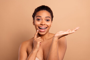 Poster - Photo of gorgeous cheerful woman hold empty space excited naked shoulders isolated on beige pastel color background