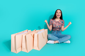 Full length photo of lucky girly woman wear print shirt rising fists open shoppers empty space isolated turquoise color background