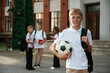 © standret - Boy is with soccer ball. Kids are near the school together, pupils