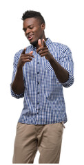 Wall Mural - Young african american man wearing blue shirt pointing fingers to camera with happy and funny face. Good energy and vibes.