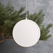© J-Gen - White blank round ceramic christmas ornament mockup. Hanging ceramic christmas element with Christmas tree branches concrete wall background.