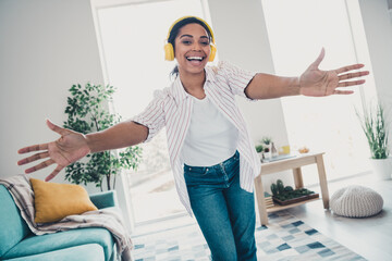 Portrait of nice young woman music headphones arms welcome you wear shirt modern interior flat indoors