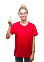 Young beautiful blonde woman wearing red t-shirt and glasses over isolated background showing and pointing up with finger number one while smiling confident and happy.