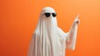 © Tetiana - Ghost wearing sunglasses pointing up with index finger on orange background