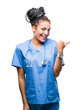 © Krakenimages.com - Young braided hair african american girl professional surgeon over isolated background smiling with happy face looking and pointing to the side with thumb up.