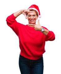 Atrractive senior caucasian redhead woman wearing christmas hat over isolated background smiling making frame with hands and fingers with happy face. Creativity and photography concept.