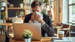 © Maria Mikhaylichenko - Businessman battling illness at work, blowing nose while seated at laptop in cozy cafe. Determination to meet deadlines despite feeling under the weather.