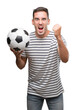 © Krakenimages.com - Handsome young man holding soccer football annoyed and frustrated shouting with anger, crazy and yelling with raised hand, anger concept