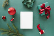 © RooM The Agency - Overhead view of a blank piece of deckle edge card  with a wrapped Christmas gift and assorted Christmas decorations on a green background