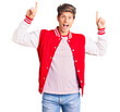 © Krakenimages.com - Young handsome man wearing baseball uniform smiling amazed and surprised and pointing up with fingers and raised arms.
