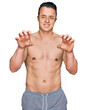 © Krakenimages.com - Handsome young man wearing swimwear shirtless smiling funny doing claw gesture as cat, aggressive and sexy expression