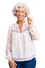 Wall Mural - Senior grey-haired woman wearing casual clothes showing and pointing up with finger number one while smiling confident and happy.