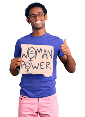 Wall Mural - African handsome man holding woman power banner smiling happy and positive, thumb up doing excellent and approval sign