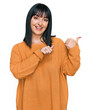 © Krakenimages.com - Young hispanic woman wearing casual clothes pointing to the back behind with hand and thumbs up, smiling confident