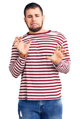 Sticker - Young handsome man wearing striped sweater disgusted expression, displeased and fearful doing disgust face because aversion reaction.